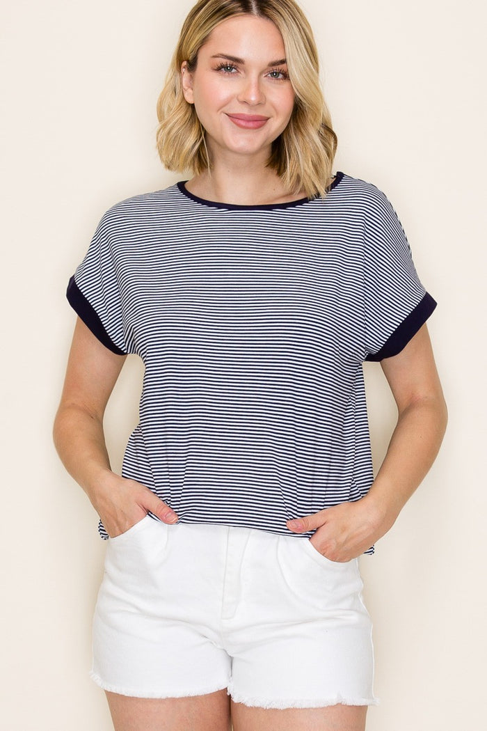 woman wearing a navy and white striped short sleeve top with rolled cuffs and white shorts