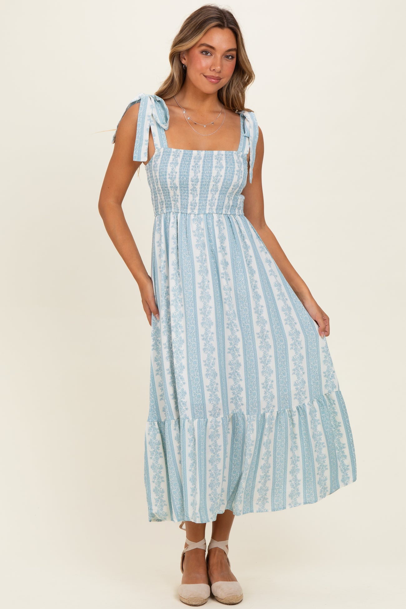woman wearing a light blue floral maxi dress with tie shoulder straps and a ruffled hem