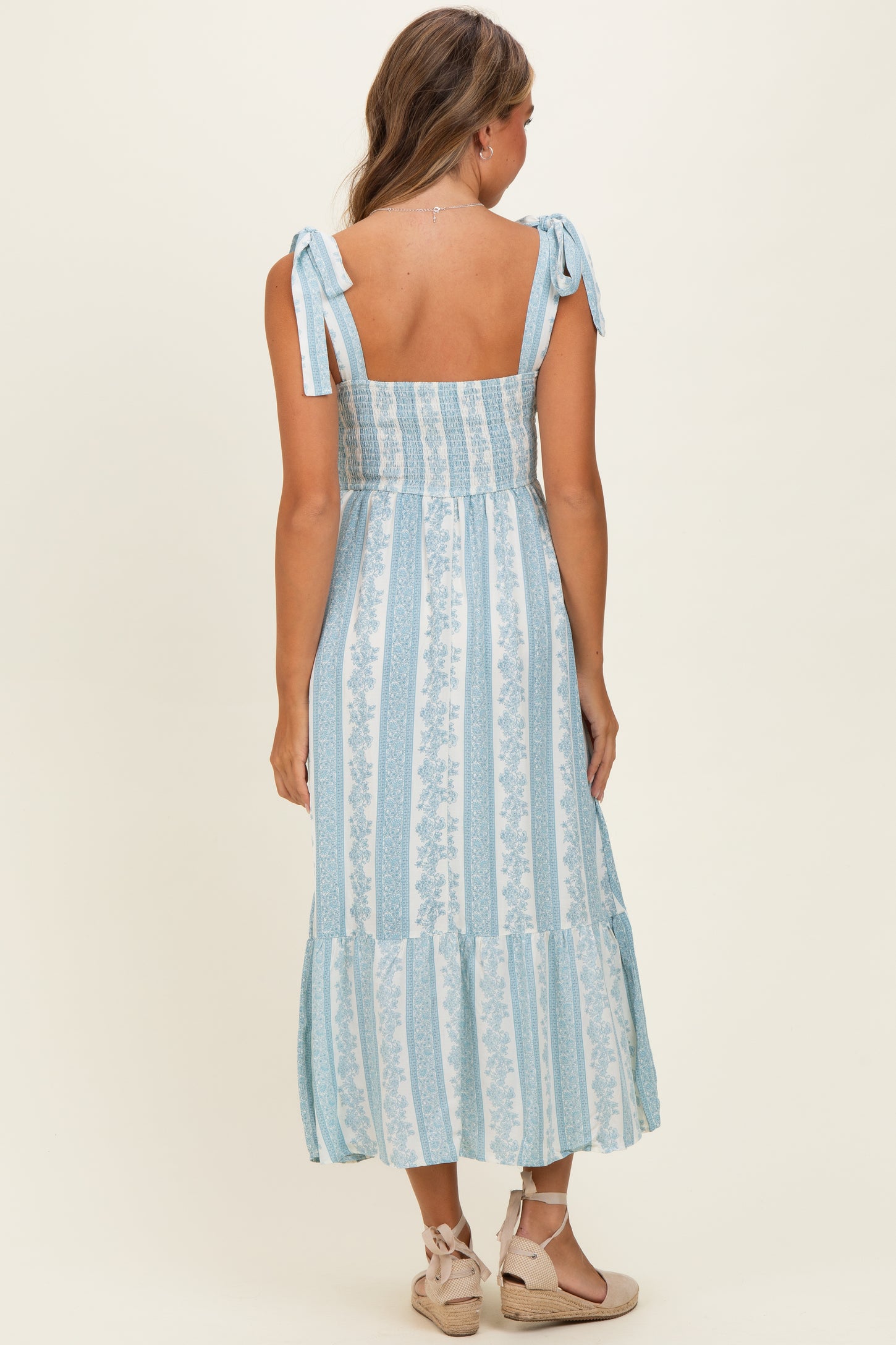 woman wearing a light blue floral print maxi dress with tie shoulder straps and a tiered skirt
