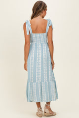 woman wearing a light blue floral print maxi dress with tie shoulder straps and a tiered skirt