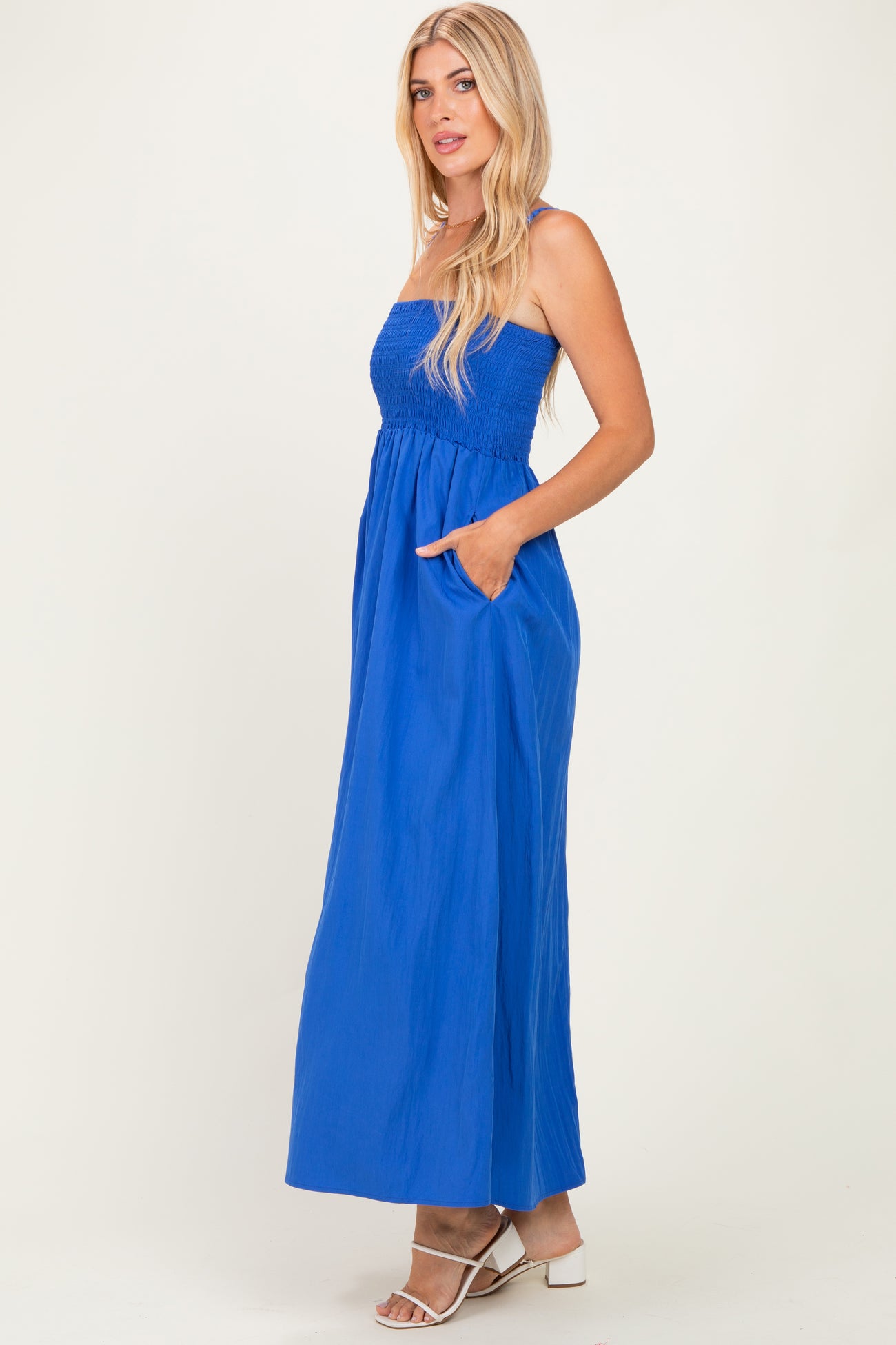woman wearing a bright blue strapless maxi dress with a smocked bodice and pockets