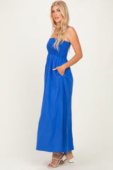 woman wearing a bright blue strapless maxi dress with a smocked bodice and pockets