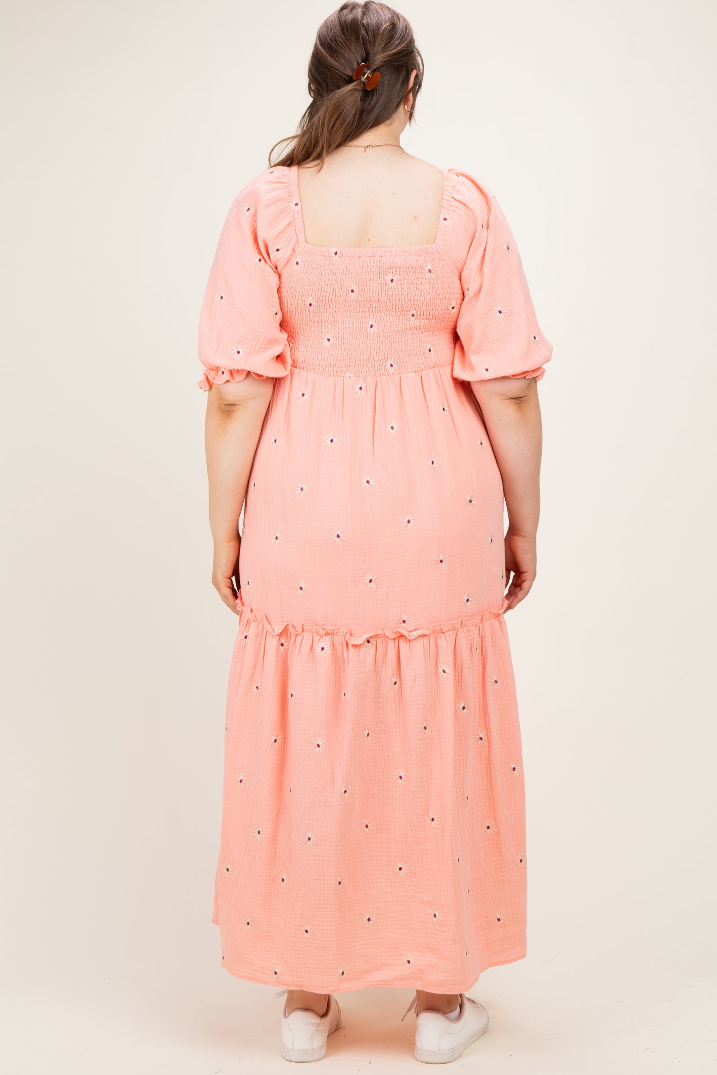 woman wearing a pink maternity plus maxi dress with puff sleeves and floral embroidery on the back
