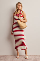 woman wearing a red and white striped ribbed midi dress, holding a straw bag and wearing beige slide sandals