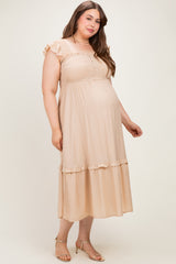 woman wearing a beige maternity plus dress with ruffle sleeves and smocked bodice, showing her baby bump