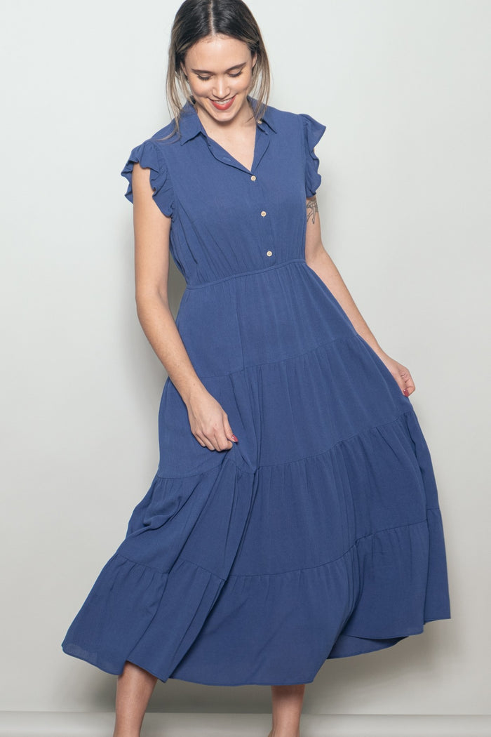 woman wearing a blue tiered midi dress with short ruffled sleeves and a button-up collar