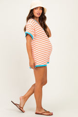 woman wearing an orange and white striped maternity shirt with blue trim and shorts, displaying a baby bump