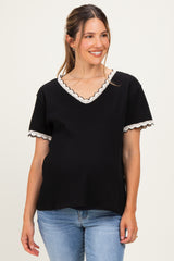 woman wearing a black maternity top with scalloped lace trim and short sleeves