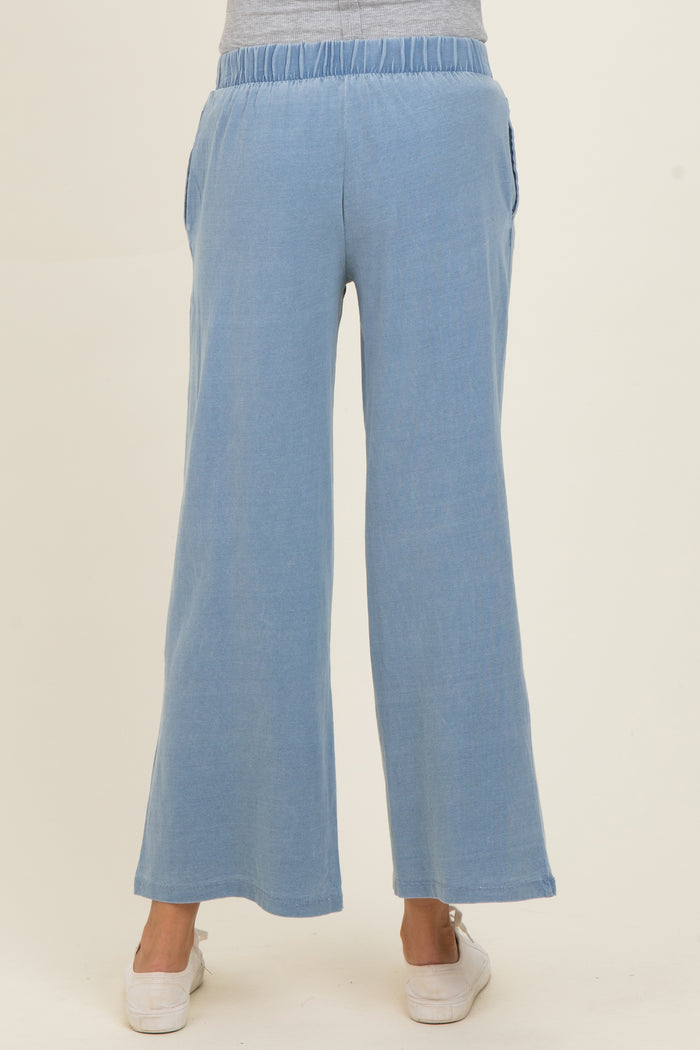 woman wearing light blue maternity wide-leg pants with elastic waistband and side pockets, showing a casual style from the back
