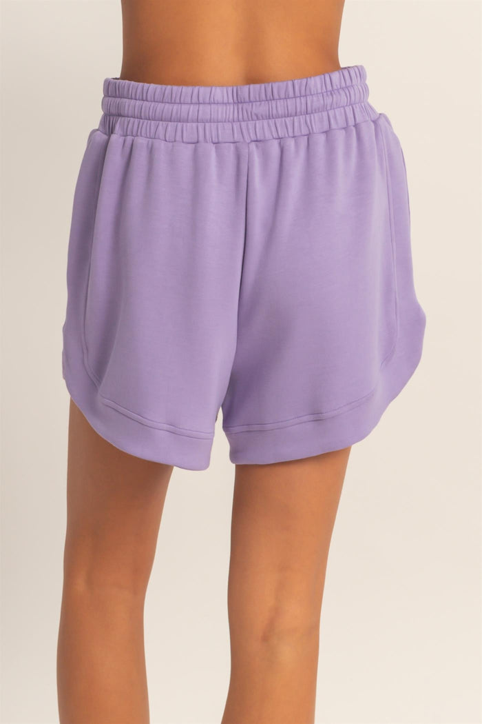 women wearing purple lightweight athletic shorts with an elastic waistband and side pockets, seen from the back