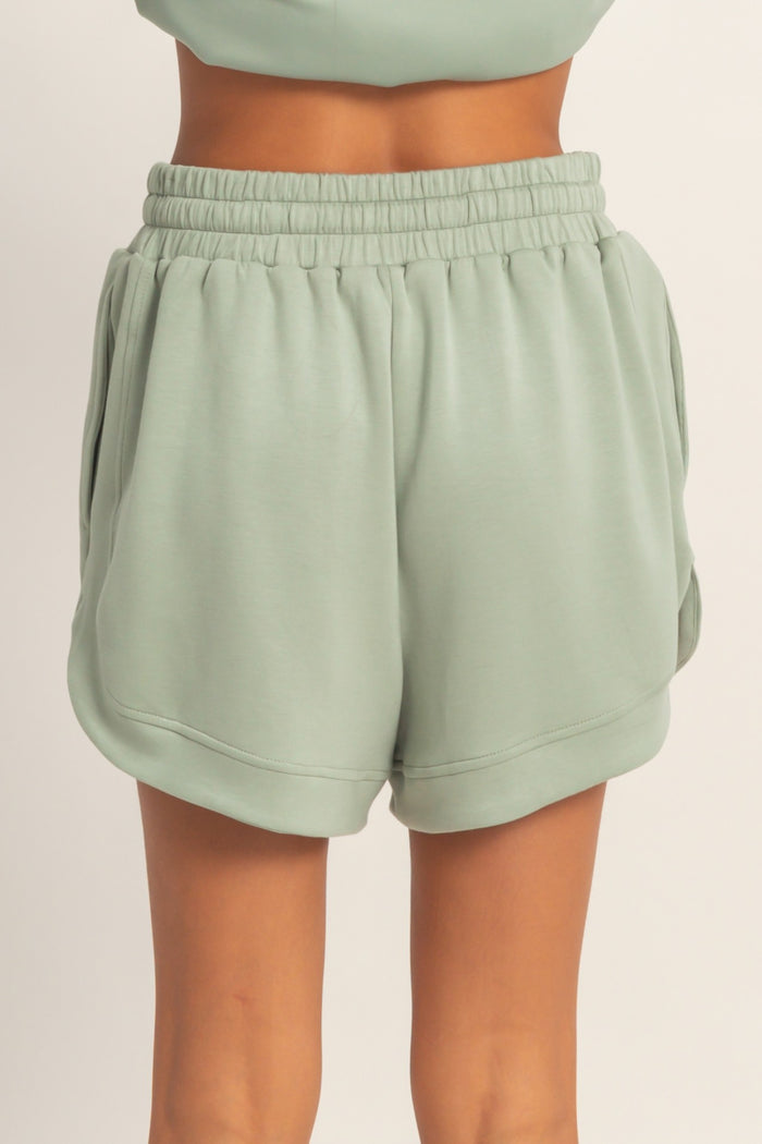 woman wearing light green casual shorts with an elastic waistband and side pockets