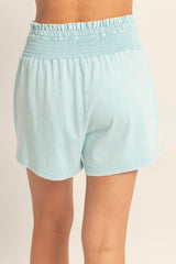 light blue smocked-waist shorts worn by a model, showing the back view