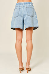 woman wearing light blue high-waisted denim shorts with an elastic waistband, shown from the back