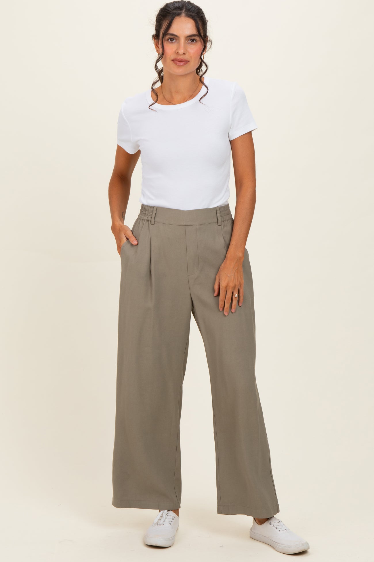 woman wearing a white short sleeve top and high-waisted khaki wide-leg pants with side pockets and white sneakers