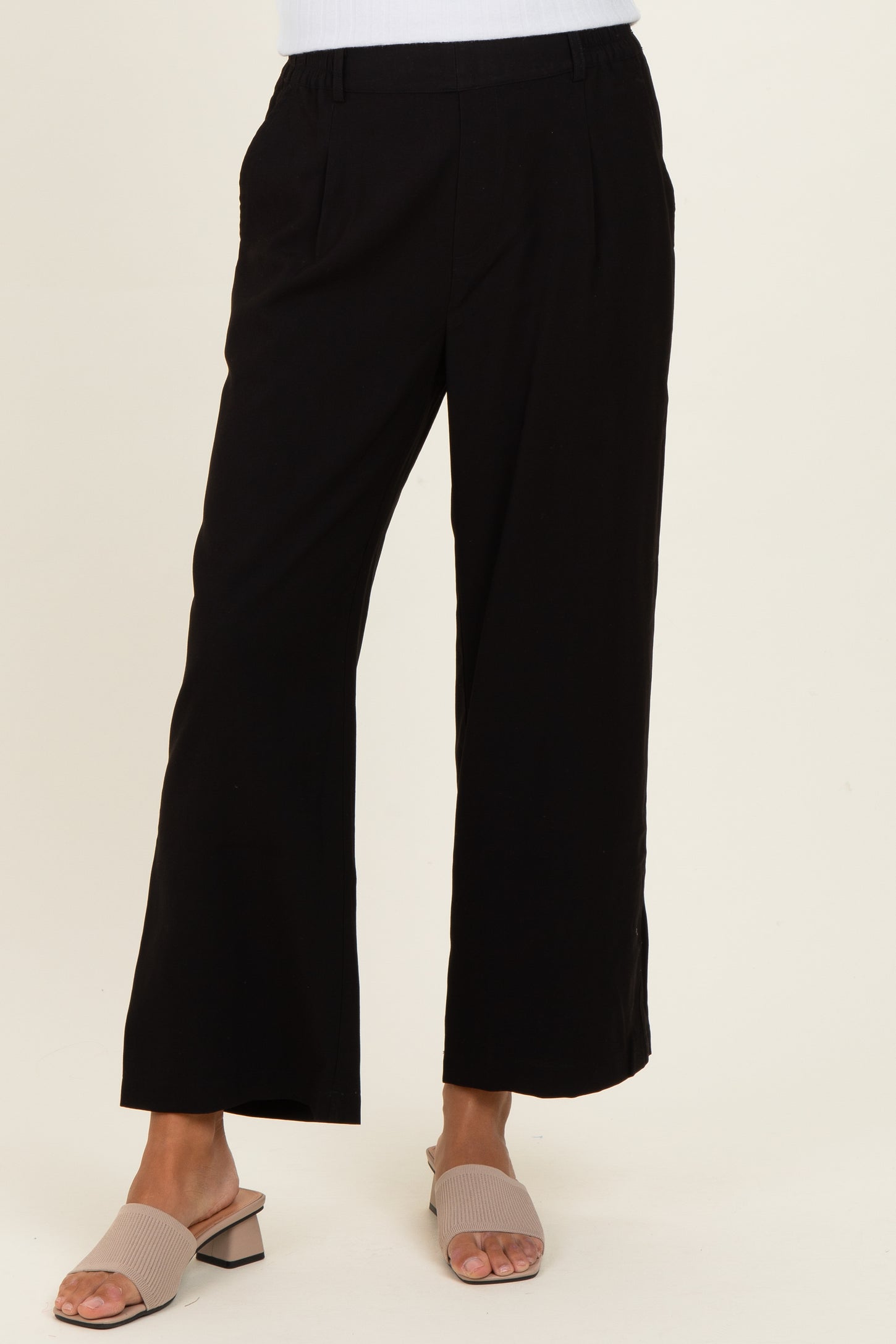 woman wearing black wide-leg trousers and beige slide sandals