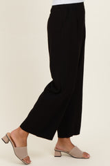 woman wearing black wide-leg trousers with pockets and beige slide sandals