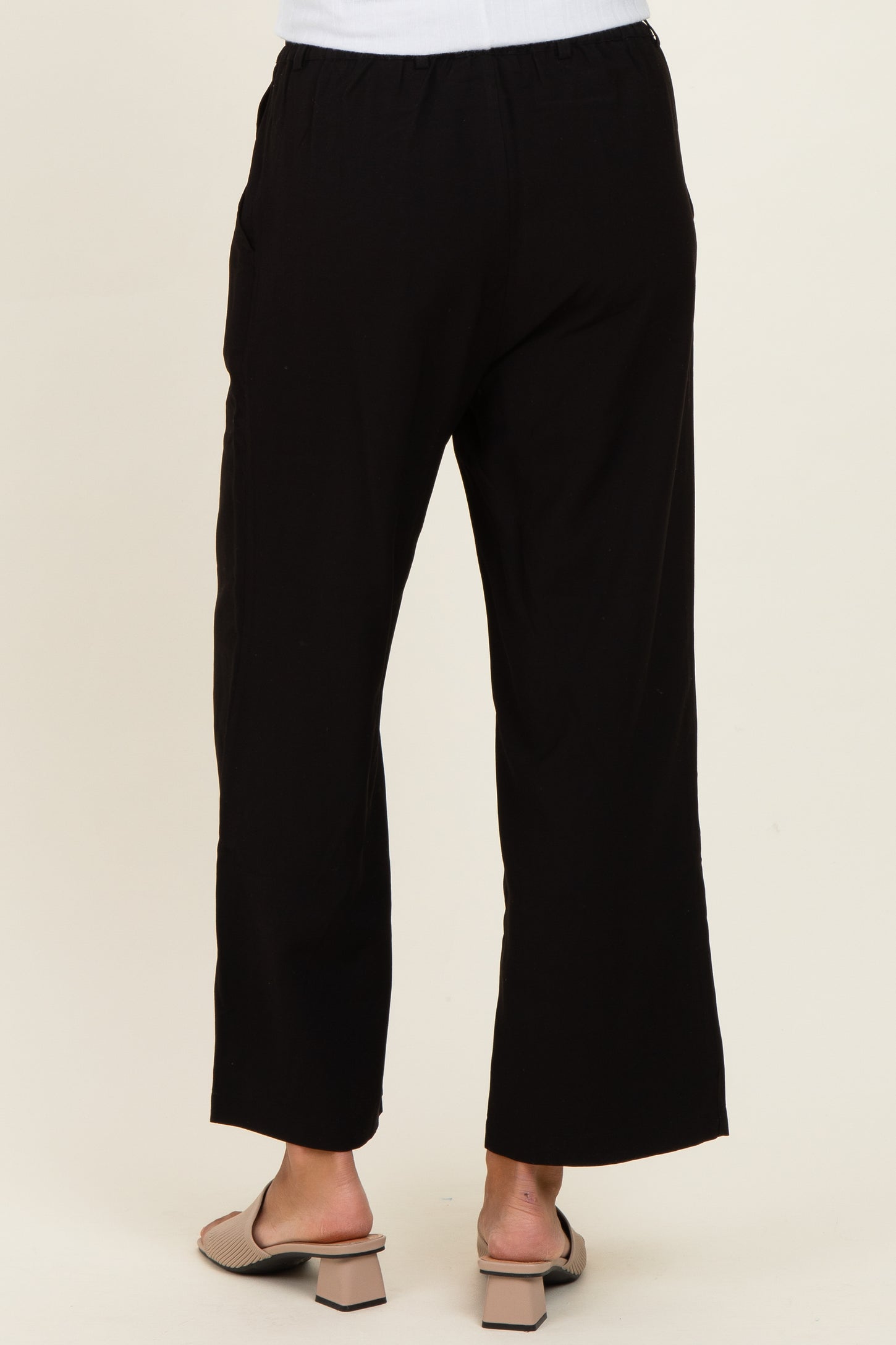 woman wearing black wide-leg pants, viewed from the back, paired with light sandals