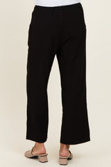woman wearing black wide-leg pants, viewed from the back, paired with light sandals