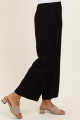 woman wearing black wide-leg trousers with pockets and beige slide sandals