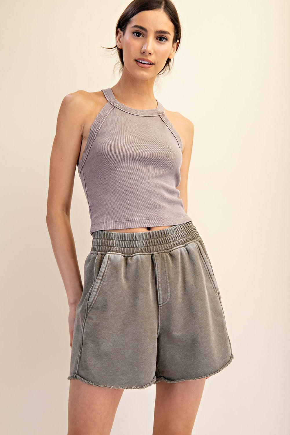 woman wearing a light gray ribbed tank top and matching high-waisted shorts with a relaxed fit