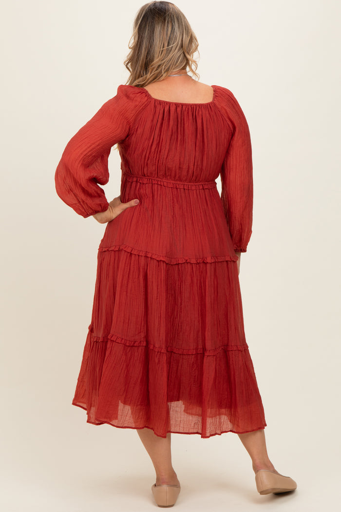 woman wearing a red tiered maxi dress with long sleeves and a smocked waist, showcasing her baby bump