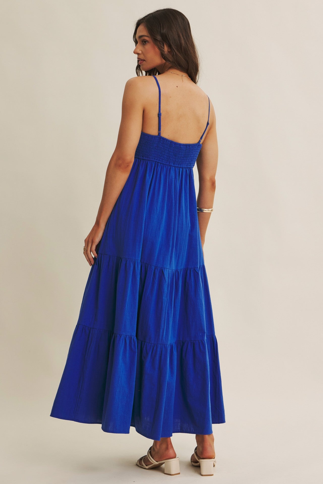 woman wearing a back view of a blue tiered maxi dress with adjustable straps and a smocked bodice