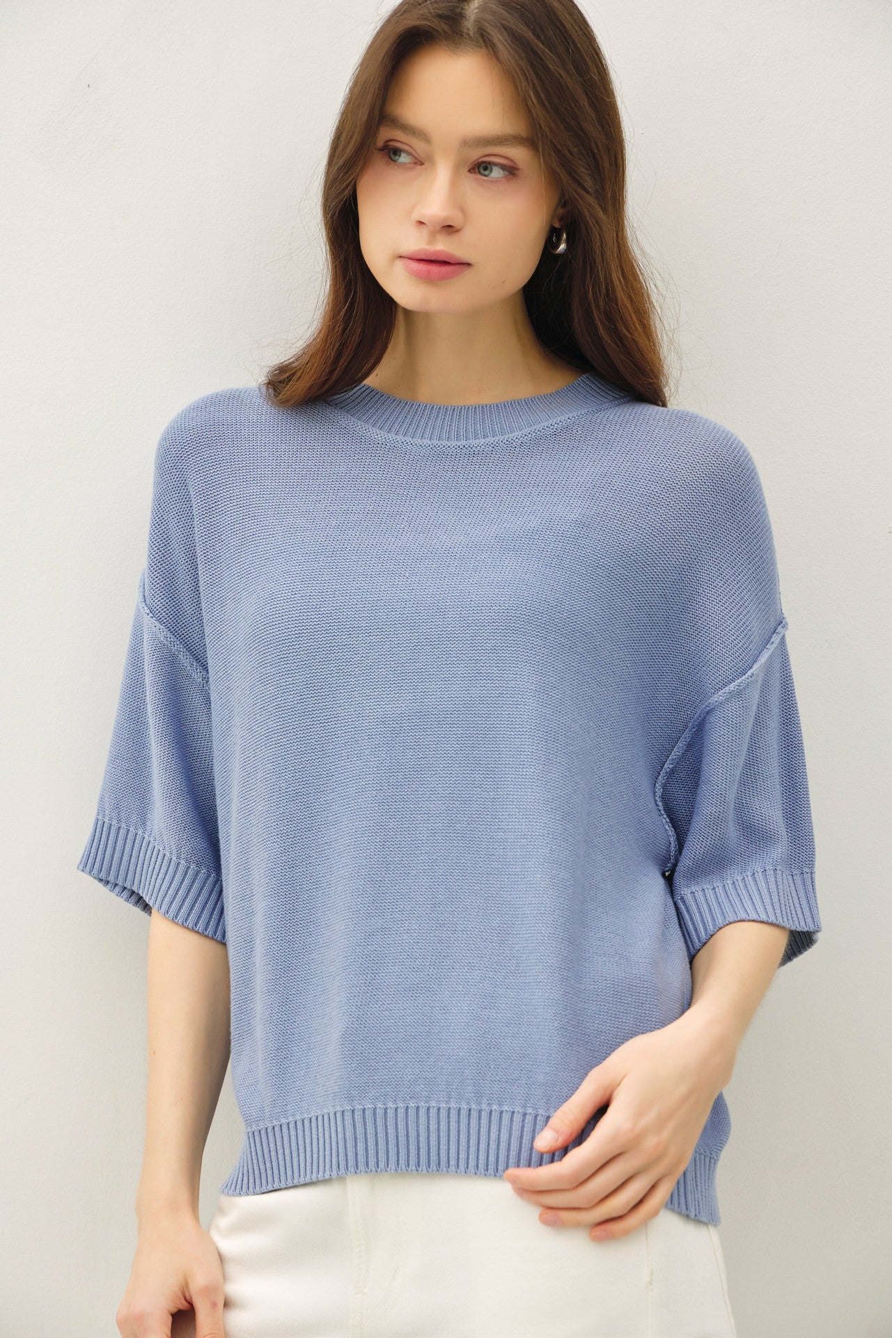 woman wearing a light blue oversized sweater with short sleeves and ribbed detailing