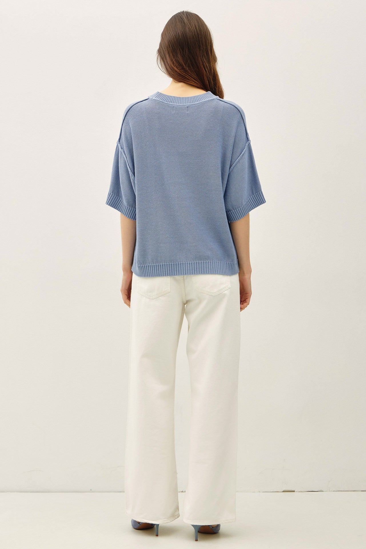 woman wearing a light blue oversized knit sweater with wide sleeves and cream-colored wide-leg pants