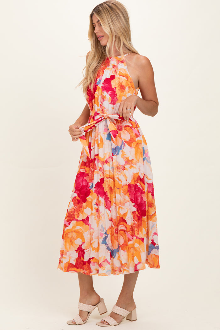 woman wearing a floral halter neck maxi dress with bright orange, pink, and blue tones.