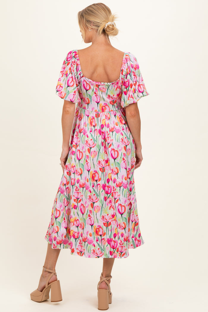 woman wearing a floral print maternity dress with puffed sleeves and a flowy skirt, showcasing a baby bump from the back