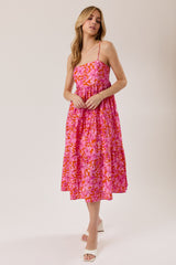 woman wearing a pink floral midi dress with spaghetti straps and a tiered skirt