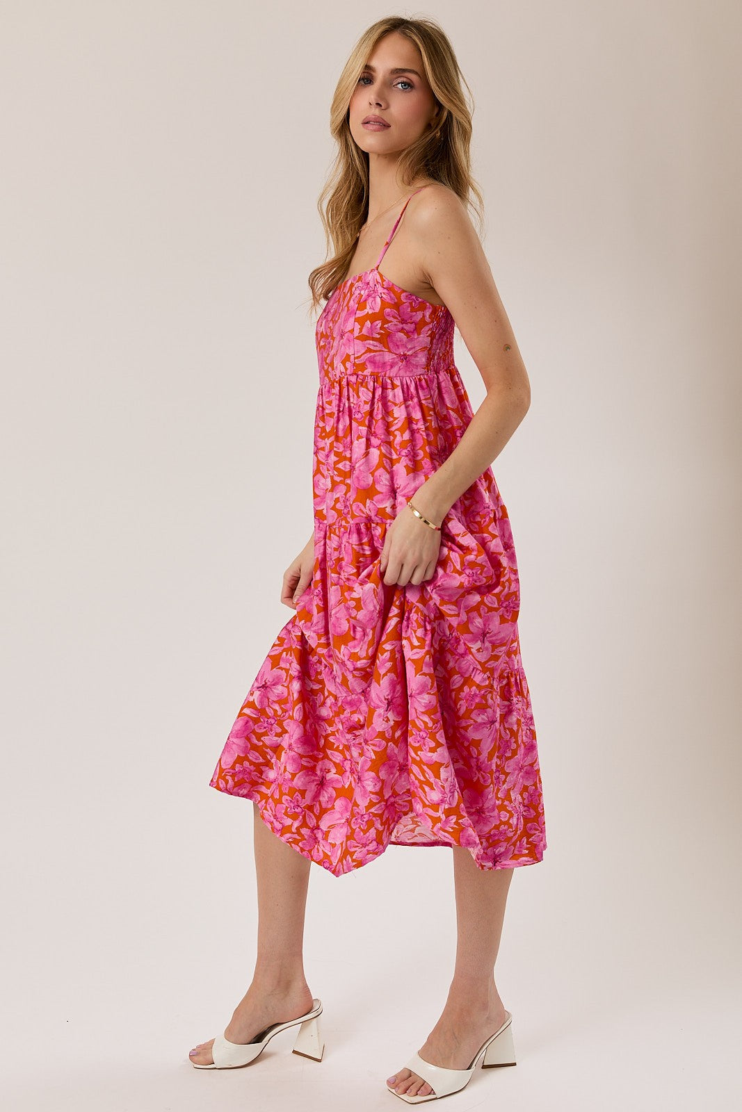 woman wearing a pink floral midi dress with adjustable straps and a flowy skirt