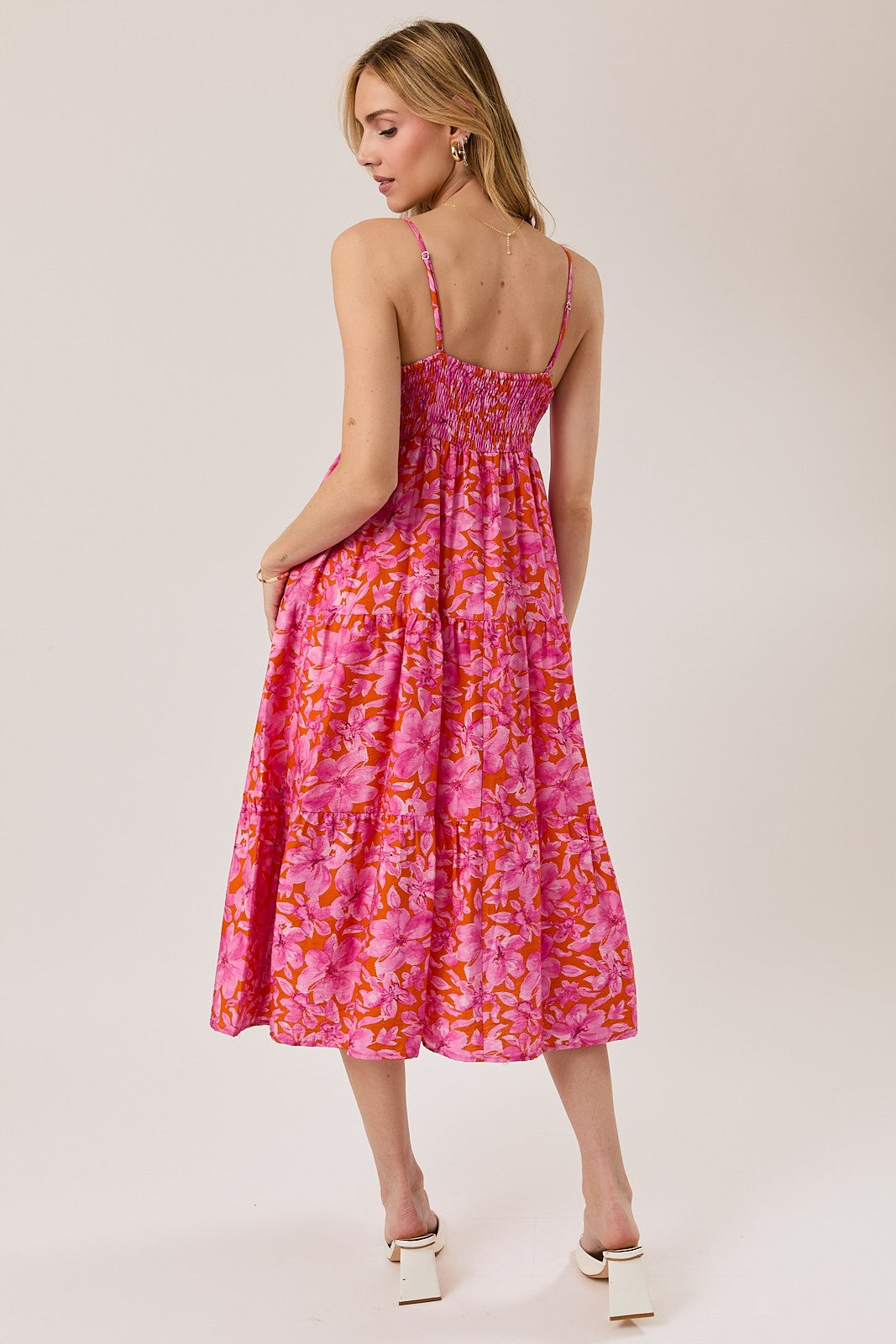 woman wearing a pink floral maxi dress with a smocked bodice and spaghetti straps, showing a flowy silhouette from the back