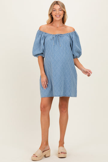 woman wearing a light blue off-the-shoulder maternity dress with puff sleeves and a tie detail