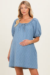 woman wearing a light blue short puff sleeve maternity dress with a scoop neckline and holding her baby bump