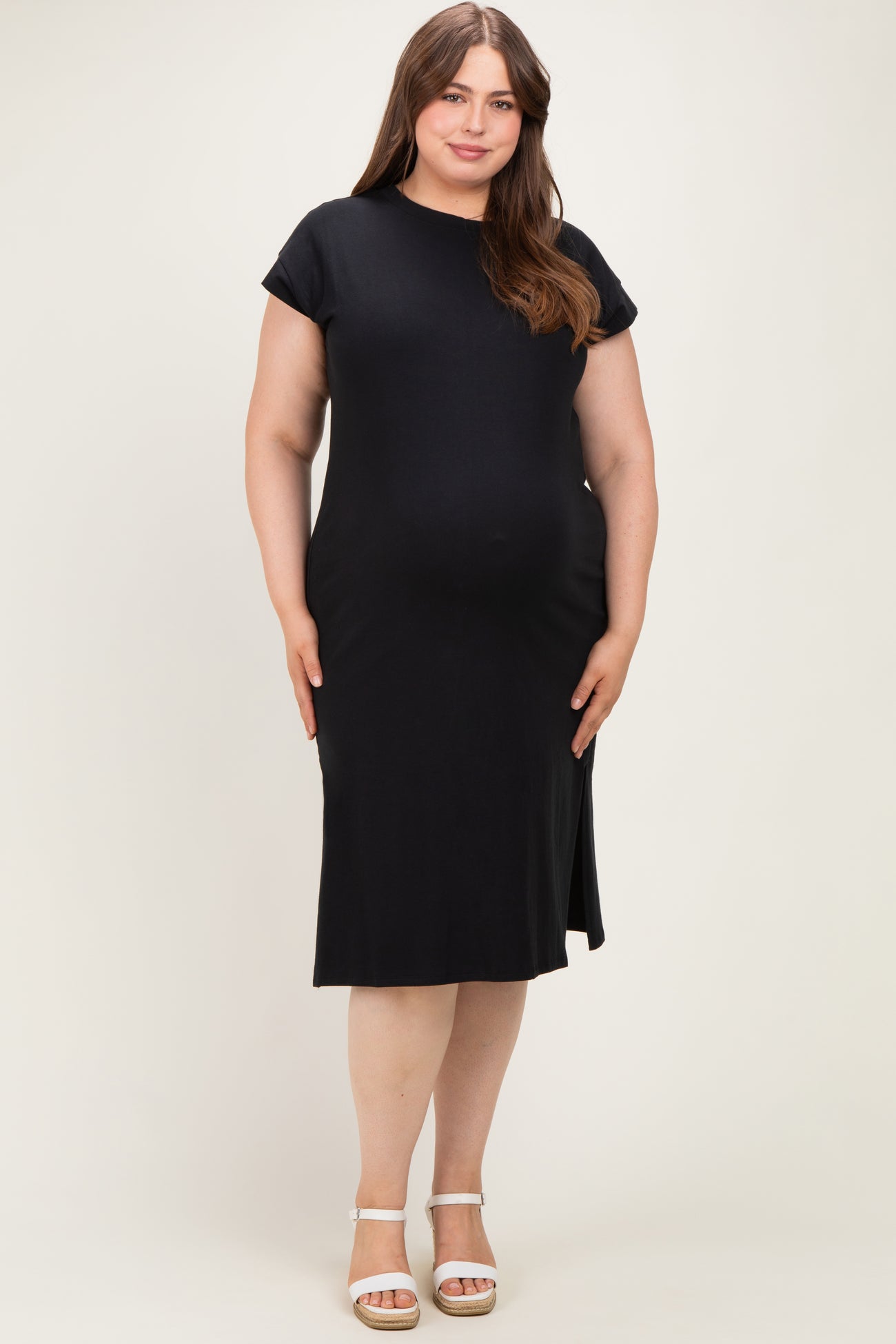 woman wearing a black short sleeve maternity dress with a side slit and a visible baby bump