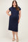 woman wearing a navy blue maternity plus dress with short cap sleeves and a relaxed fit, showcasing her baby bump