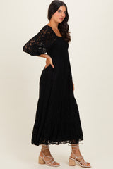 woman wearing a black lace long sleeve maxi dress and strappy sandals standing in profile
