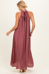 woman wearing a burgundy halter neck maternity maxi dress with a tie at the back