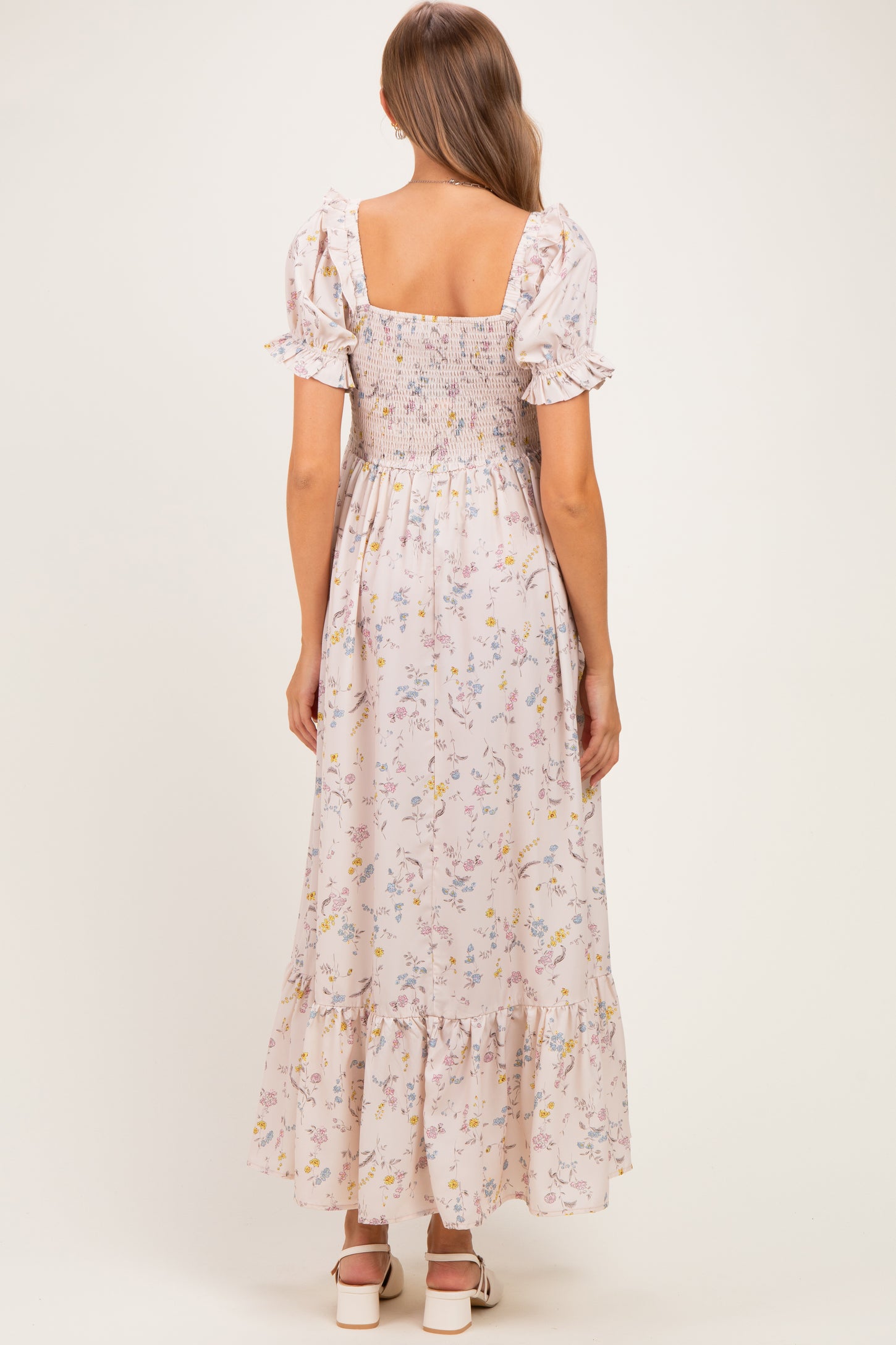 woman wearing a floral smocked maternity maxi dress with short puff sleeves and ruffled hem, seen from the back