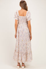 woman wearing a floral smocked maternity maxi dress with short puff sleeves and ruffled hem, seen from the back