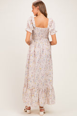 woman wearing a light pink floral maternity maxi dress with smocked bodice and ruffle sleeves, view from the back