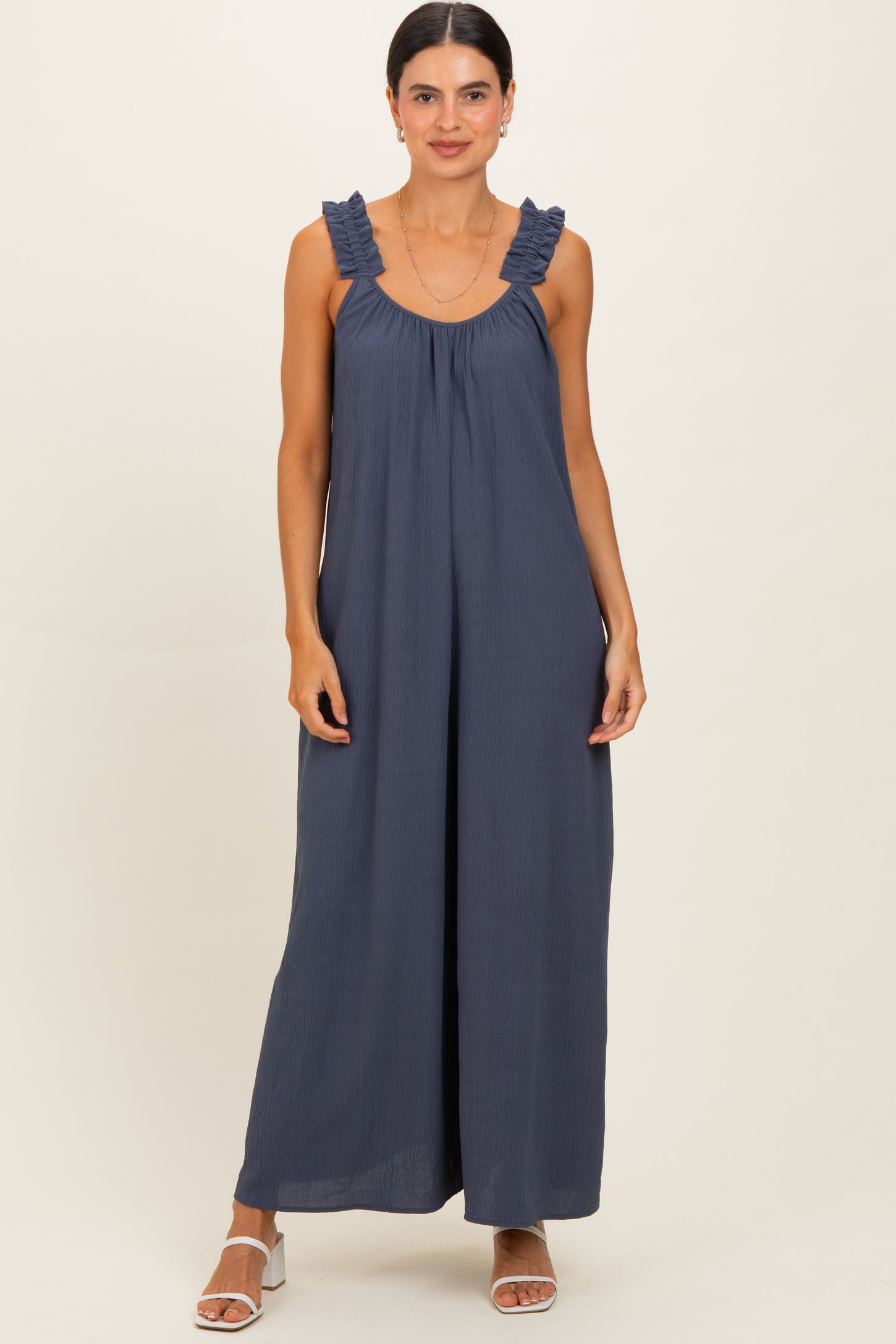 woman wearing a navy blue sleeveless maxi dress with ruffled straps and a flowy fit