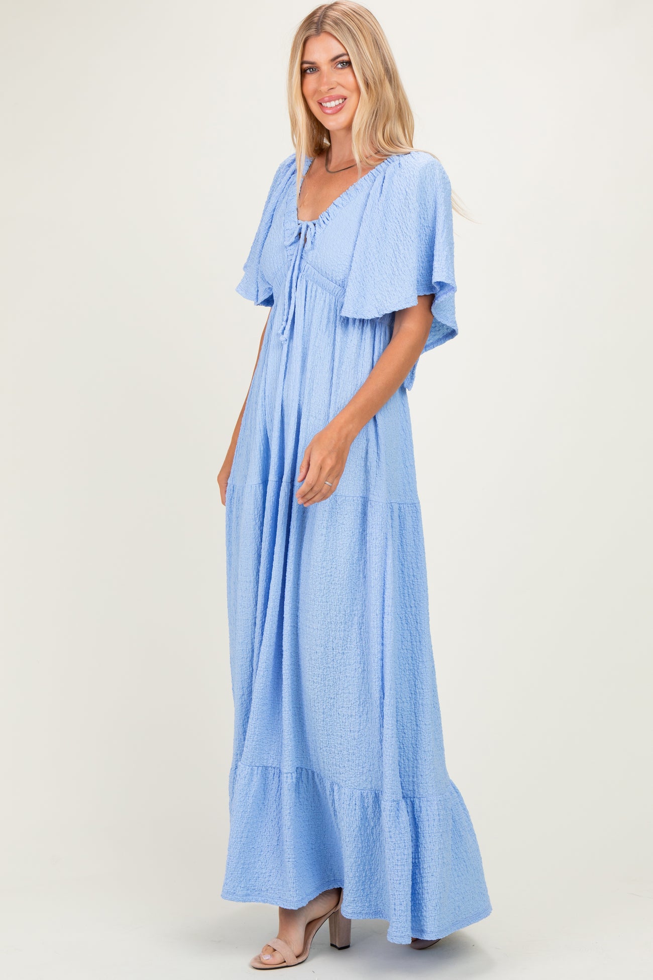 woman wearing a light blue maxi dress with flutter sleeves and a tie-front detail