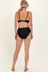 woman wearing a black two-piece bikini set with a high-waisted bottom and adjustable straps, seen from the back