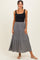 woman wearing a black sleeveless top and a flowy black and white patterned maxi skirt
