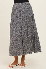 woman wearing a navy blue floral maxi skirt with a tiered design and elastic waistband