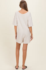 woman wearing a light beige short sleeve maternity romper, showing a relaxed fit and back view