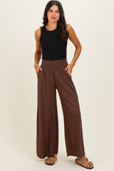 woman wearing a black sleeveless top and brown wide-leg pants with a smocked waistband