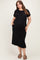 woman wearing a black short sleeve maternity plus dress with pockets, standing and showcasing her baby bump